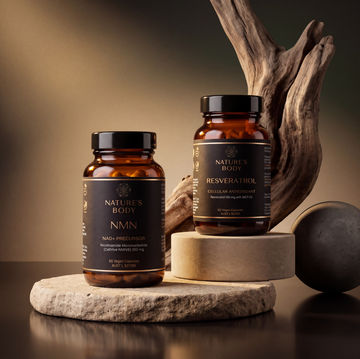 Nature’s Body NMN and Resveratrol bottles on a stone surface with driftwood in the background